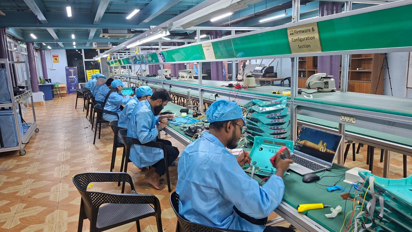 Technicians in ESD coats testing and configuring IoT devices on DMA's firmware and final integration line in Bangladesh
